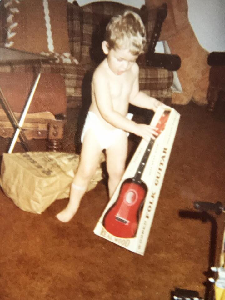 a baby in diaper playing with a guitar