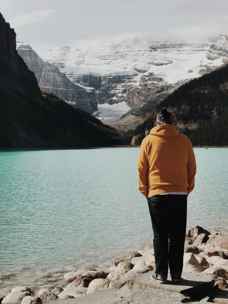 a man standing on a rocky shore by a lake