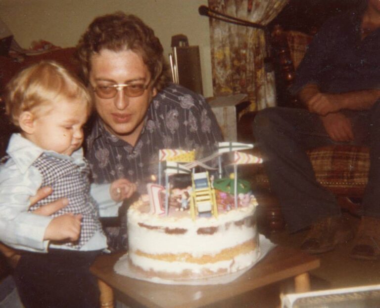 a man and a baby sitting in front of a cake